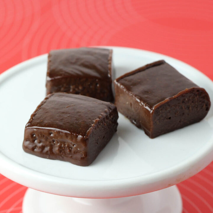 three pieces of fudge on a white plate with a red background