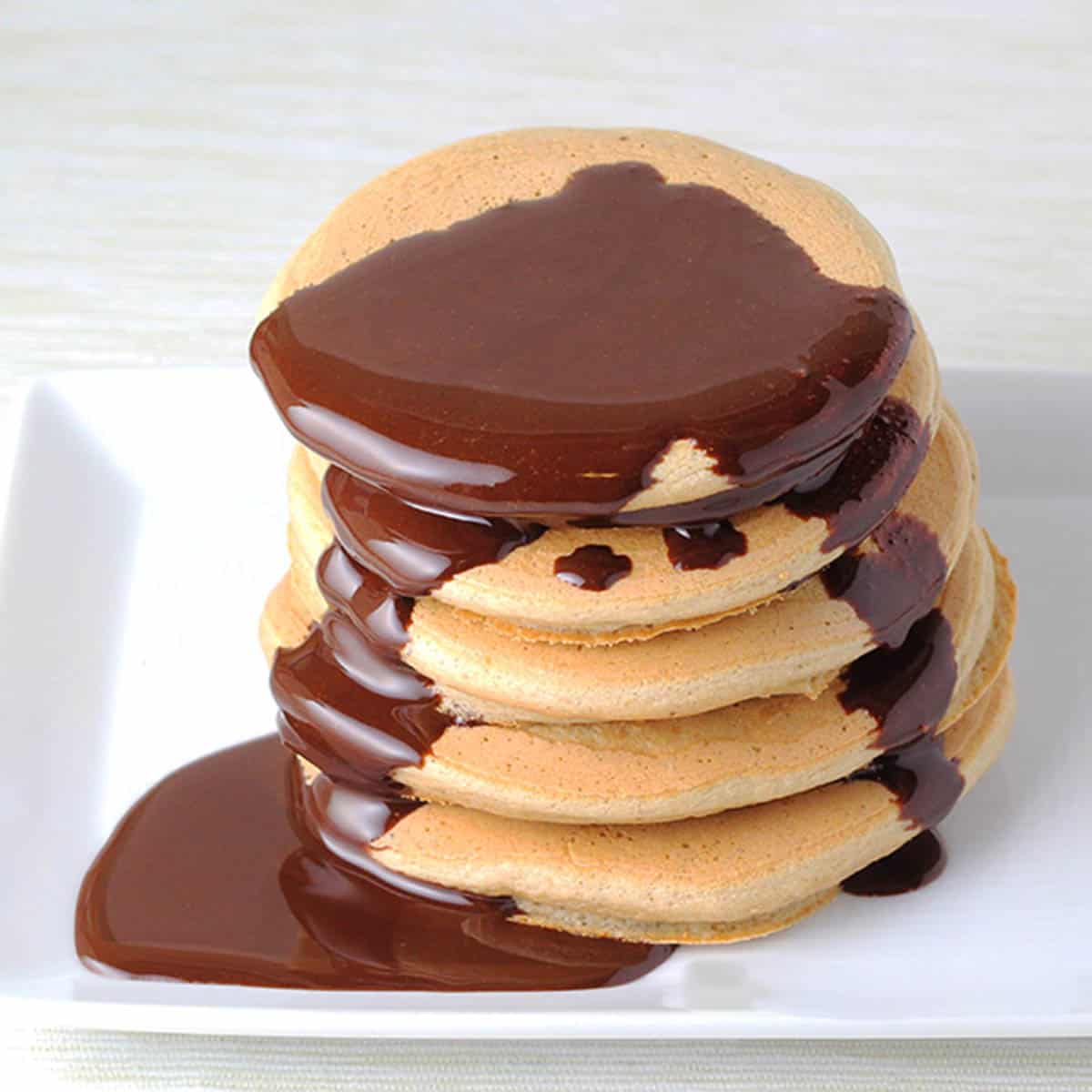 stack of protein pancakes with chocolate syrup dripping