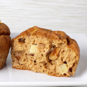 inside view of an apple peanut protein muffin on a white plate with a beige background