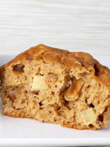 inside view of an apple peanut protein muffin on a white plate with a beige background