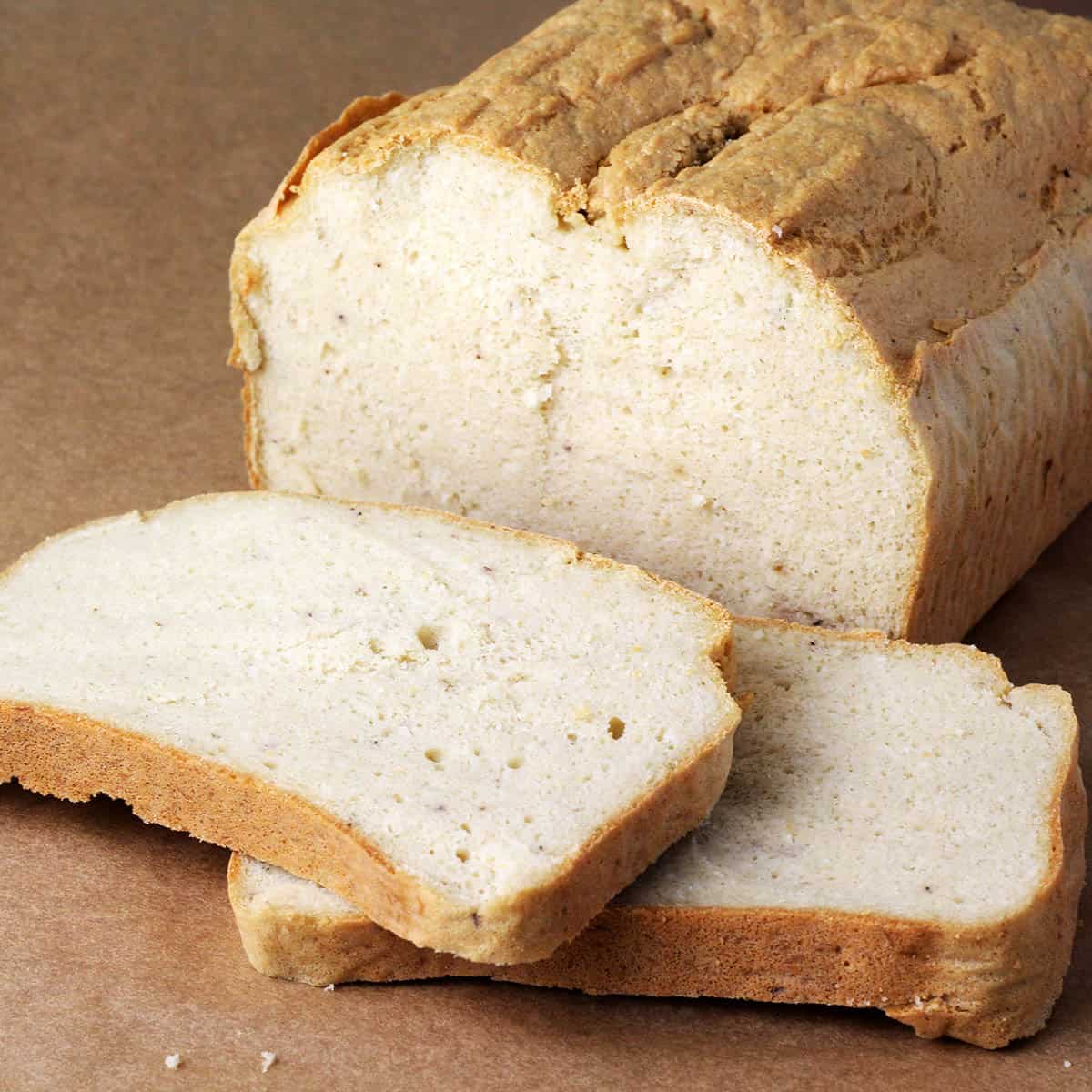 a cut loaf of protein bread with two slices down in front on an unbleached sheet of parchment paper