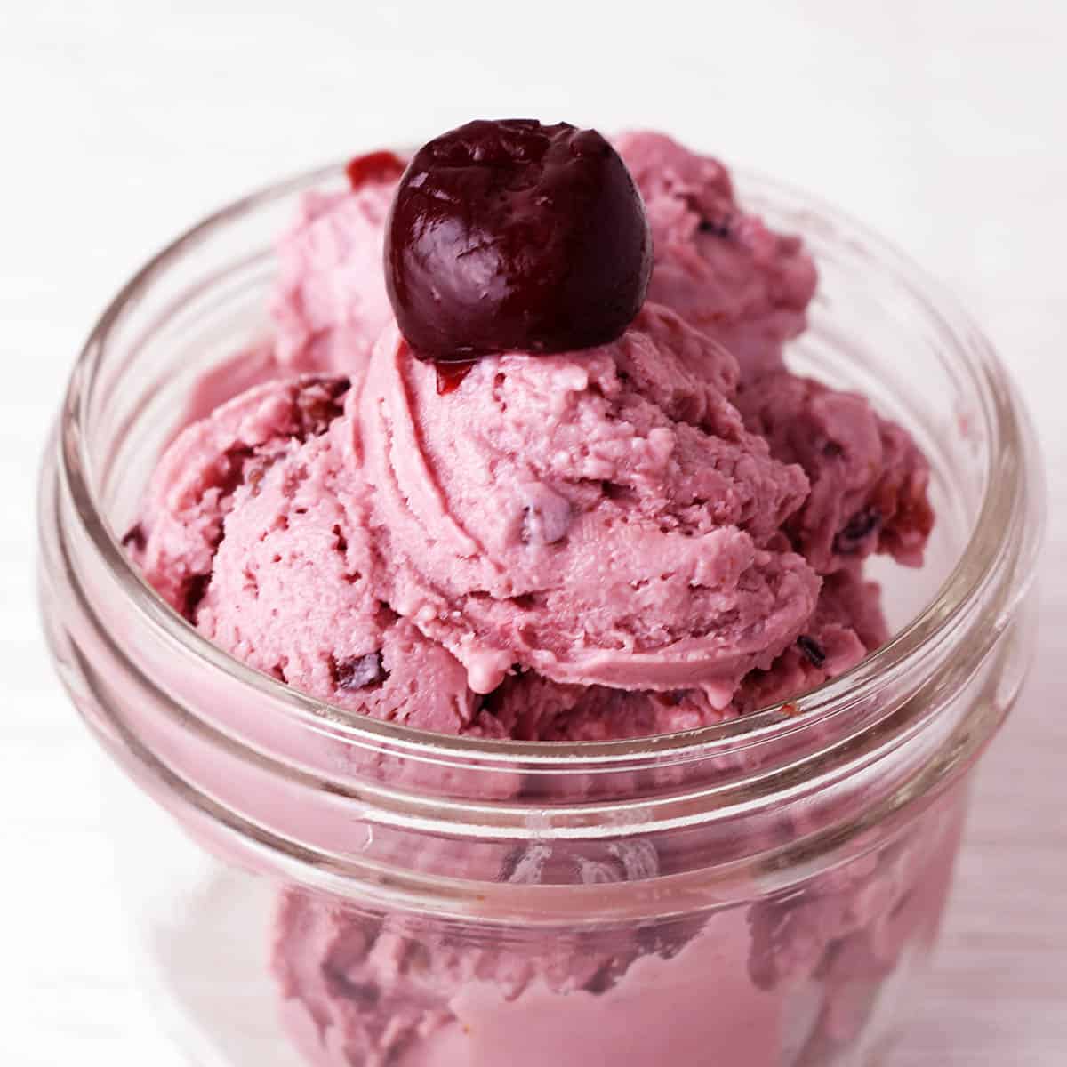 cherry frozen yogurt in a small jar with a cherry on top