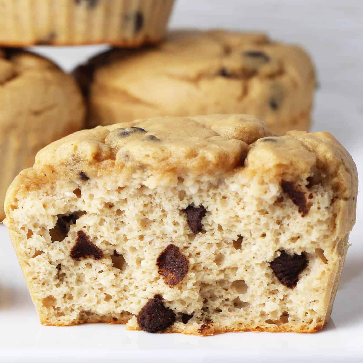 inside view of a chocolate chip muffin with a few more muffins in the background