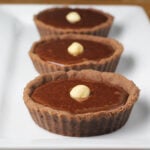 three chocolate hazelnut tartets going front to back on a white plate