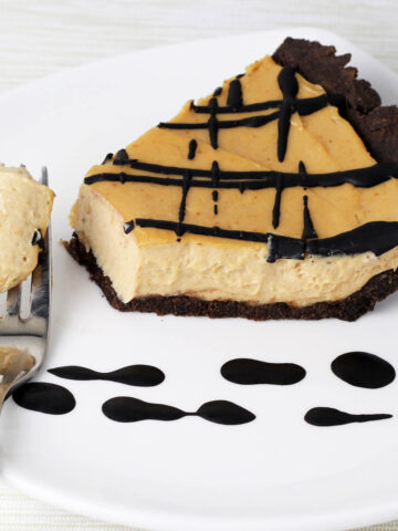 slice of chocolate peanut butter pie with chocolate crust and chocolate drizzle and a forkful of creamy pie pulled from the slice