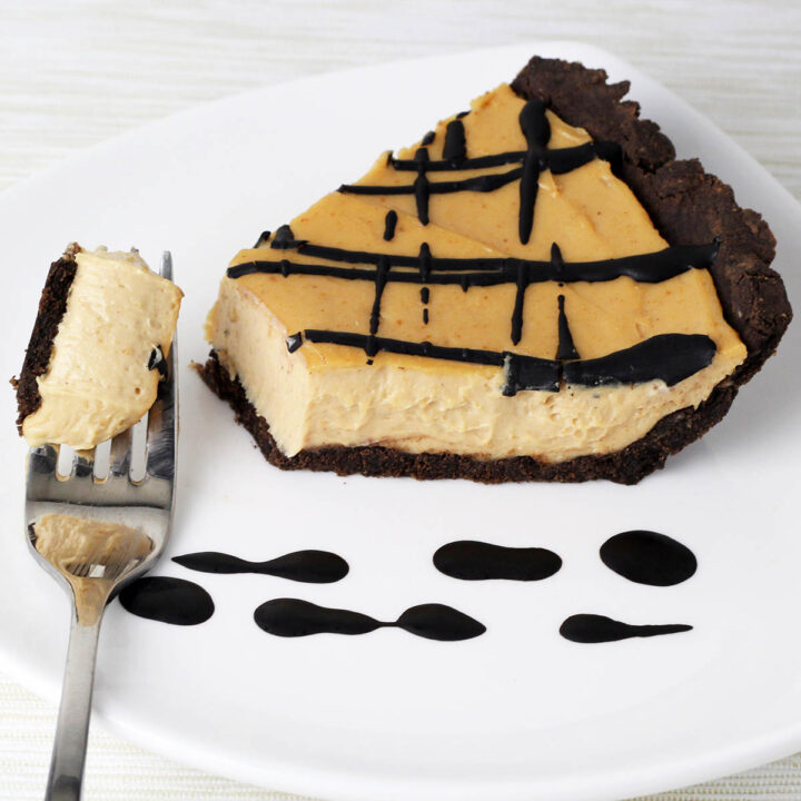 slice of chocolate peanut butter pie with chocolate crust and chocolate drizzle and a forkful of creamy pie pulled from the slice