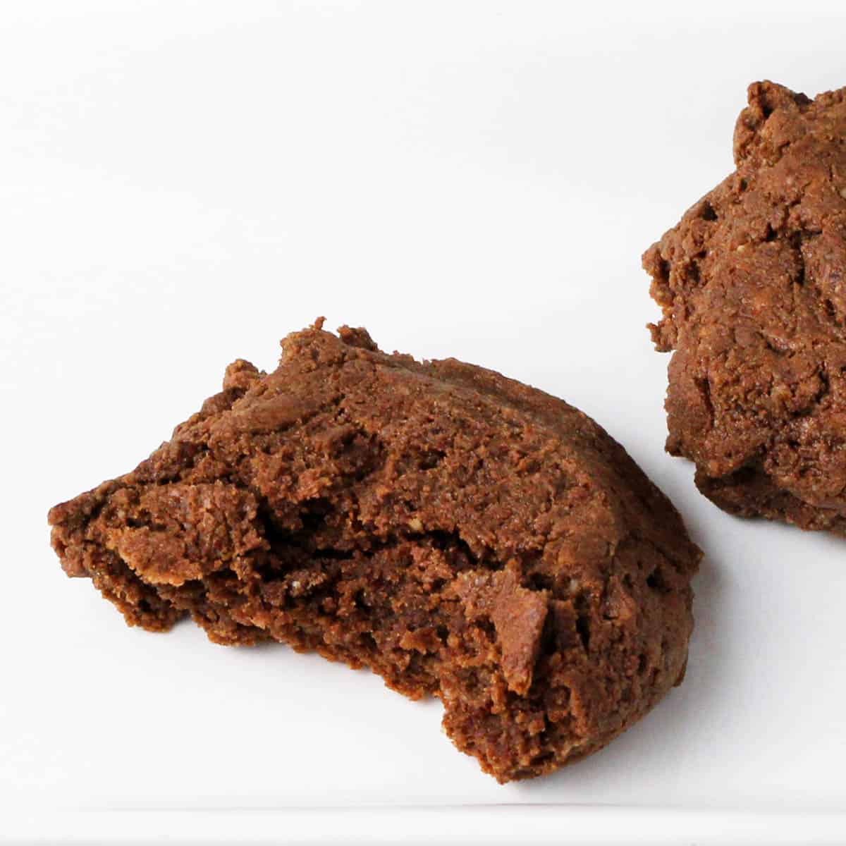 a bitten chewy chocolate protein cookie on a white plate