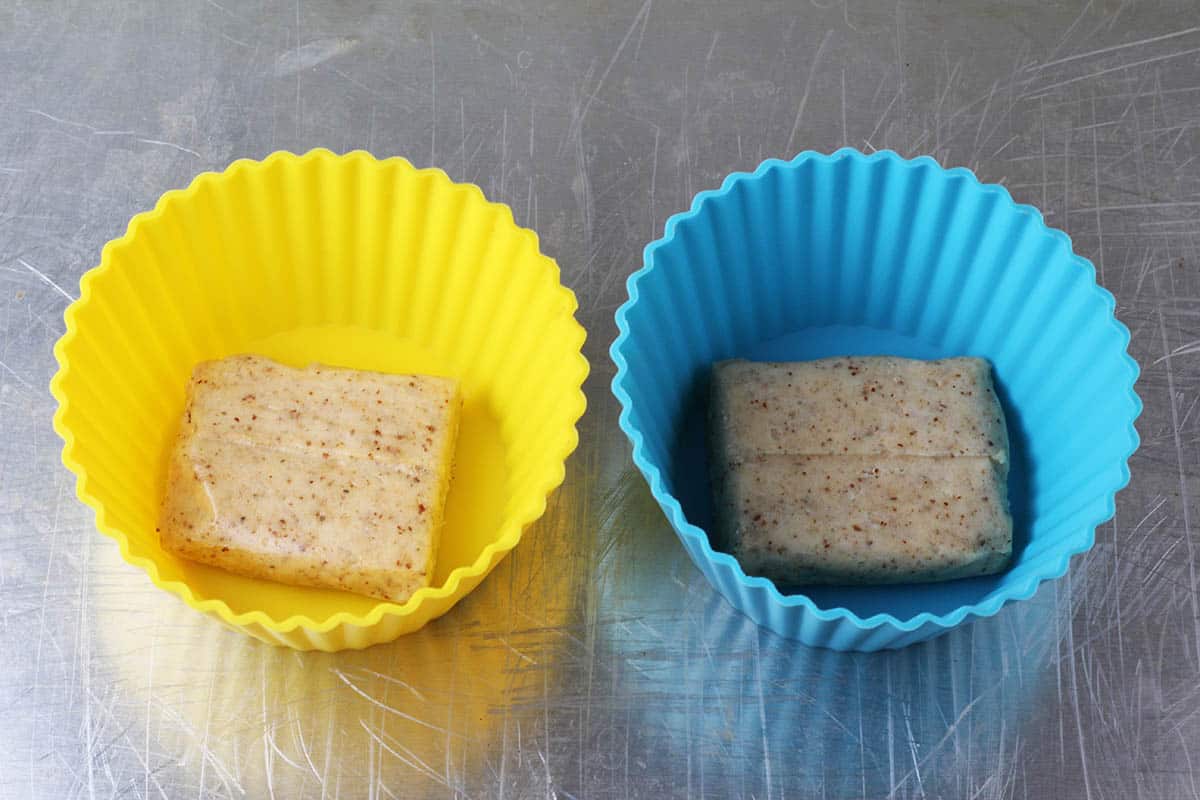 two large silicone muffin cups each with a half of coconut quest bar in them