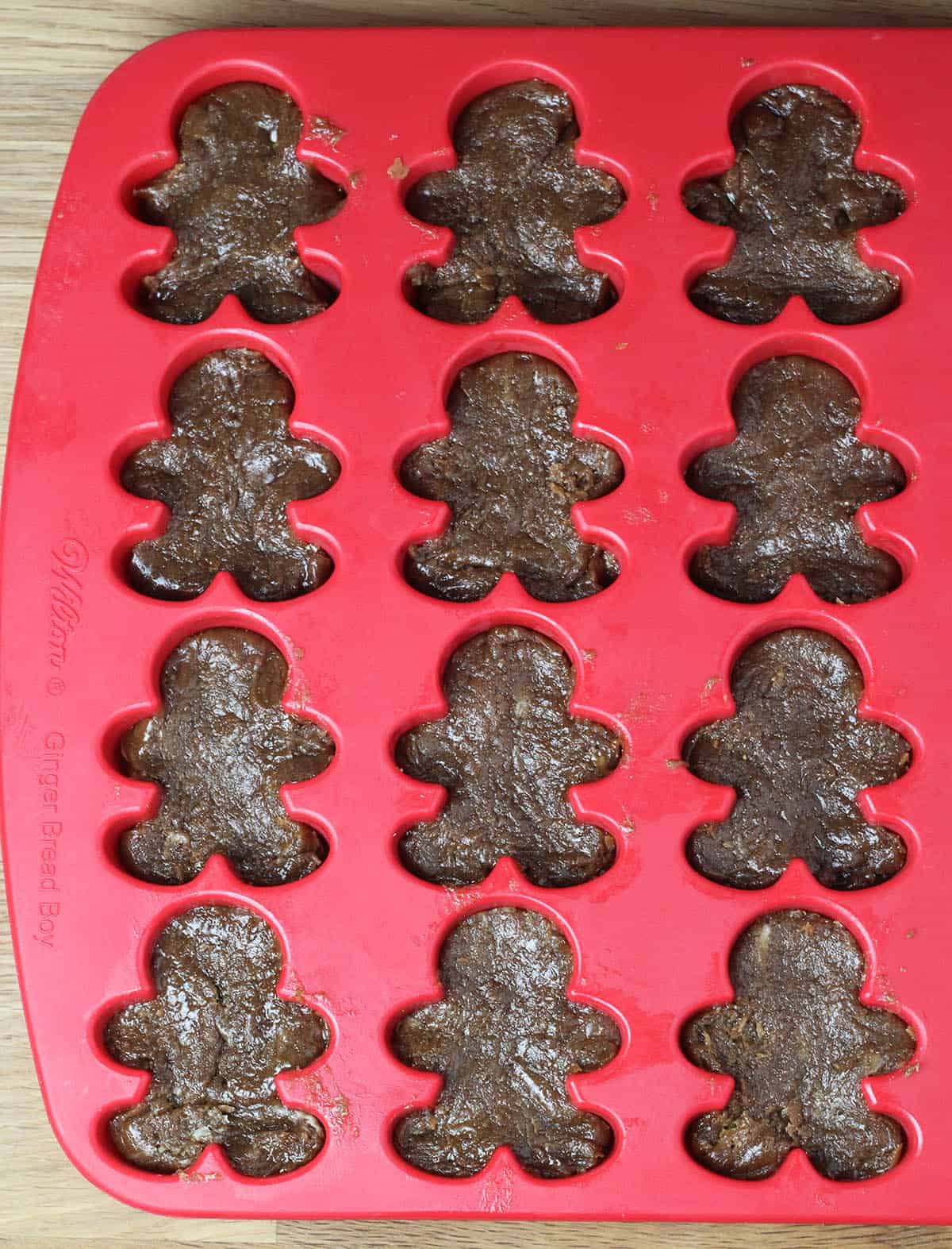red silicone candy mold with gingerbread man shaped cavities filled with gingerbread protein fudge