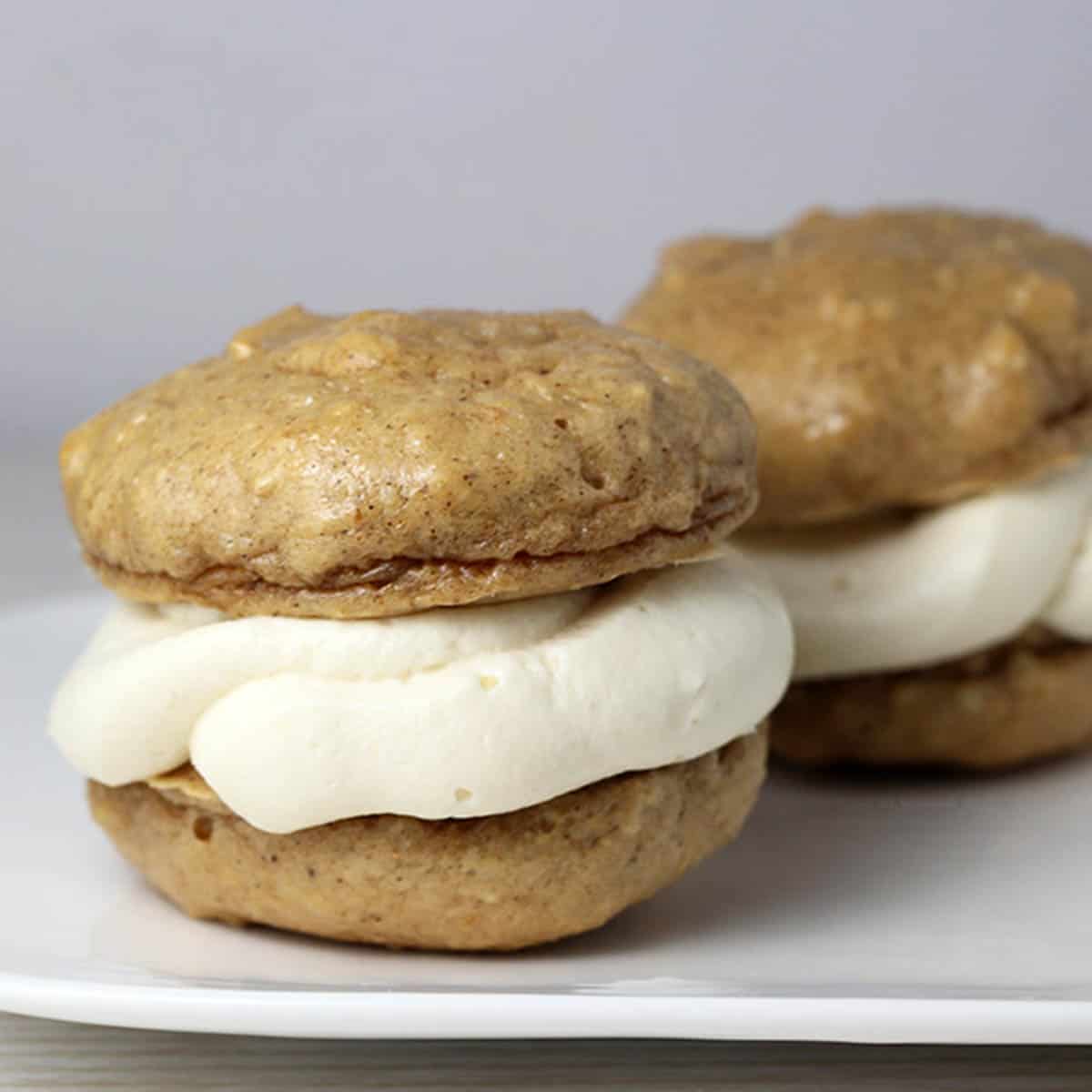 two gingerbread whoopie pie cookies on a white plate with a light background