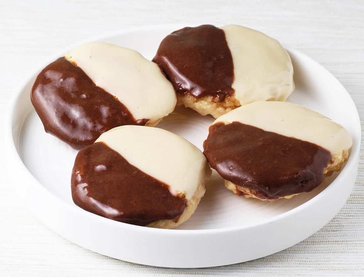 four mini black and white cookies on a round white plate