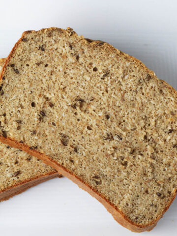 two slices of rye bread with caraway seeds on a white plate