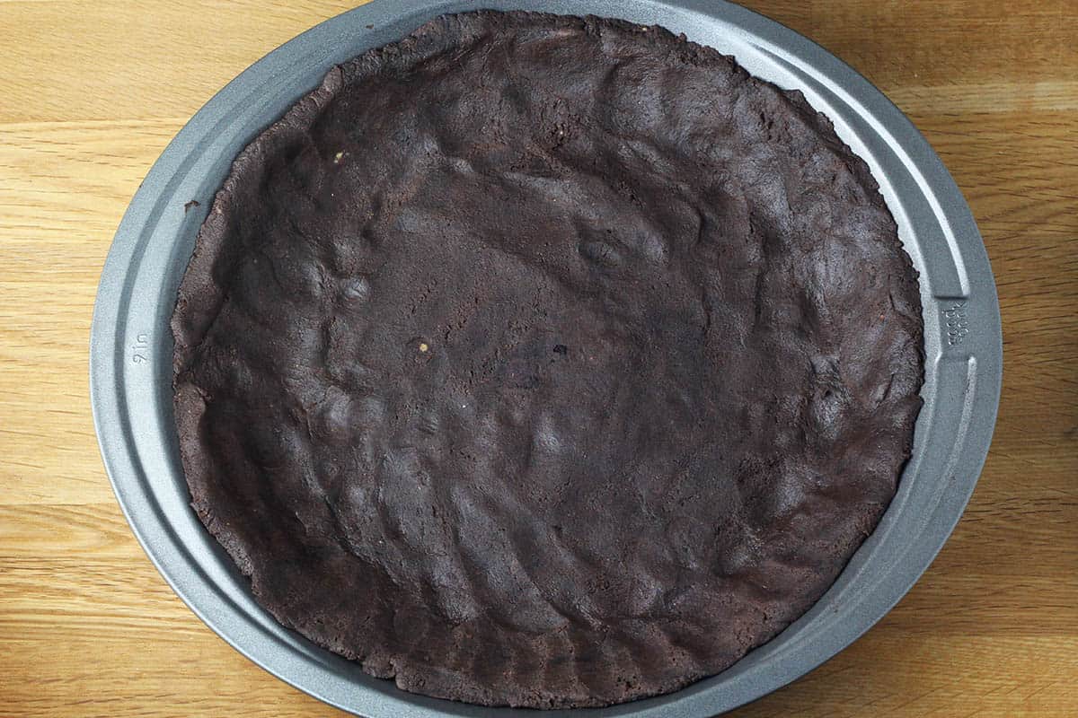dark chocolate pie crust in a metal pie pan on a wooden table