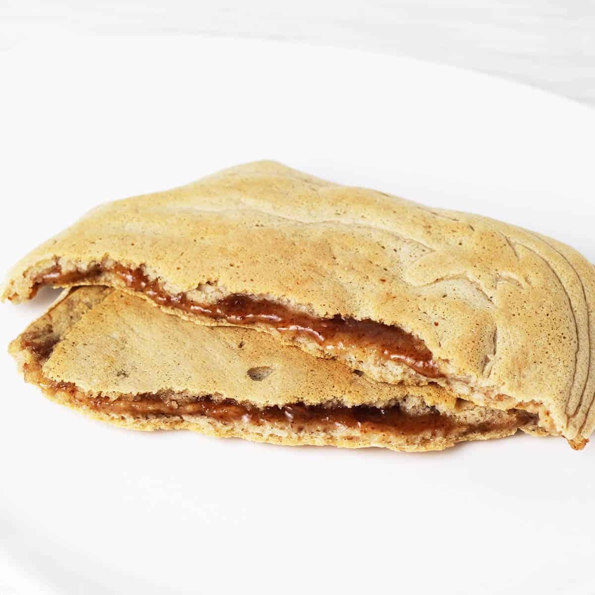 two halves of pancake stuffed with maple almond butter on a white plate