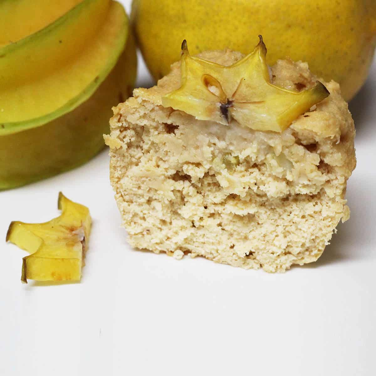 half a meyer lemon star fruit cupcake with the fruits in the background and a sliced star fruit on top of the cupcake