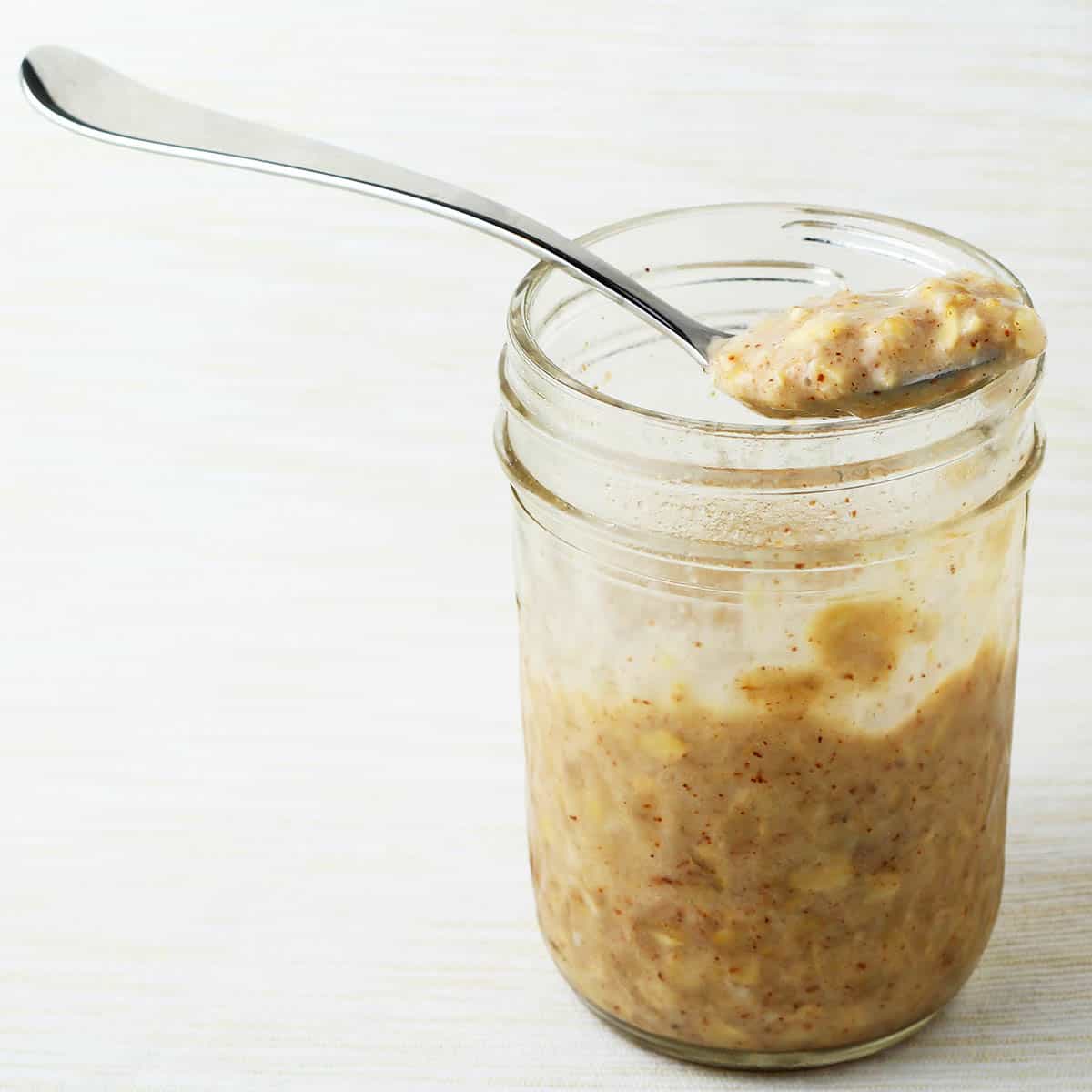 overnight protein oats in a jar with a spoonful on top on a beige background