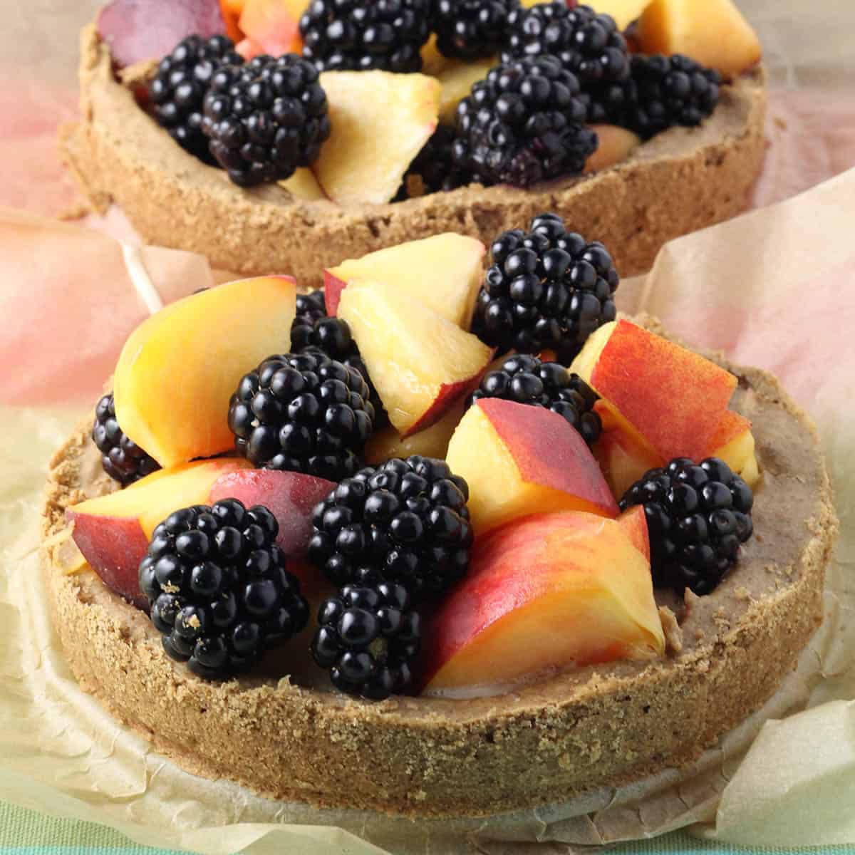two small tarts filled with peaches and blackberries, one in front and one behind