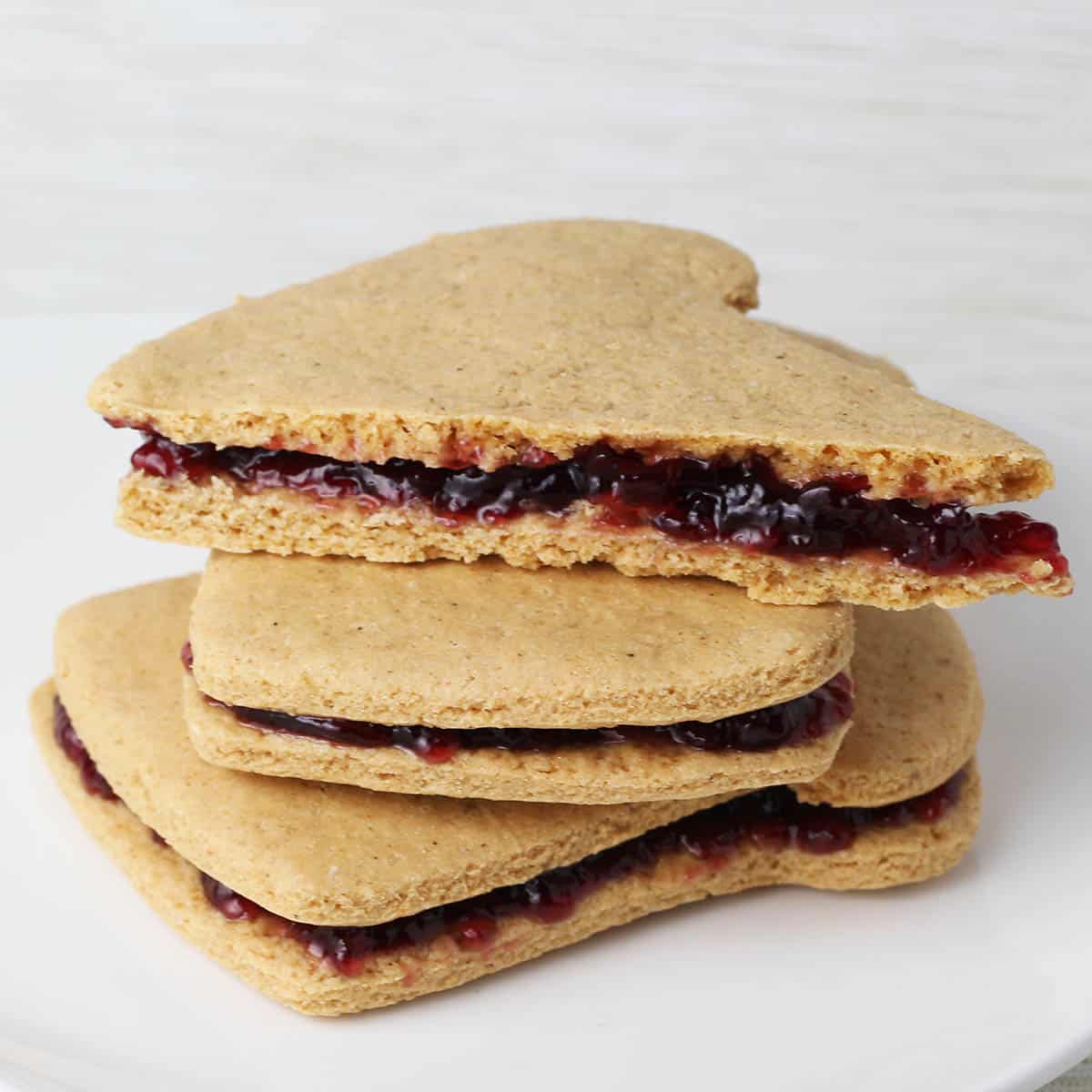 three stacked sandwich-shaped sandwich cookies, peanut butter cookies with jelly filling