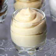 shot glass filled with peanut butter cream cheese frosting on a glass cake plate