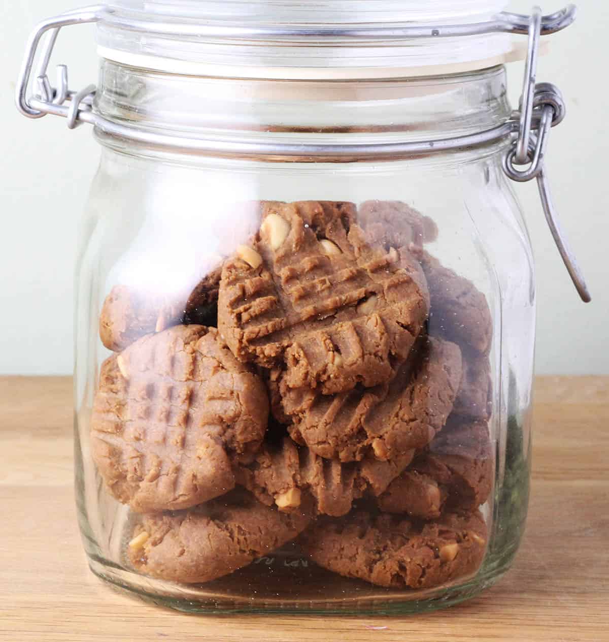 clear glass jar of peanut butter cookies on a wooden table