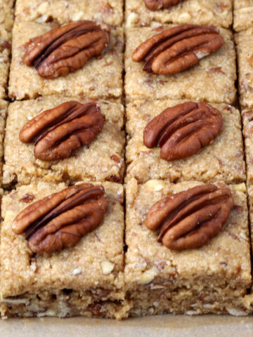 close up of freshly cut pecan protein squares, each topped with a pecan half