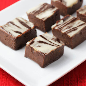 chocolate fudge with white peppermint swirls on a white plate on a red linen.