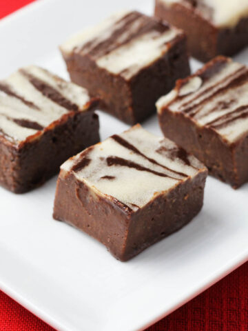 chocolate fudge with white peppermint swirls on a white plate on a red linen