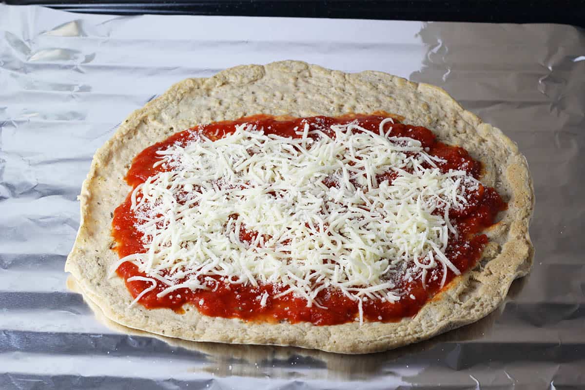 protein pizza wrap ready to go into the broiler, on a foil lined broiler pan with unmelted cheese