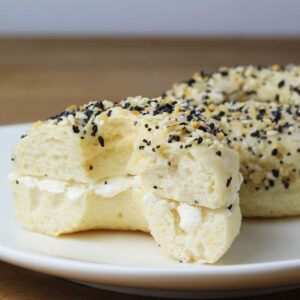 everything protein bagels sliced with cream cheese inside on a white plate
