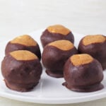 six buckeye treats on a white plate.