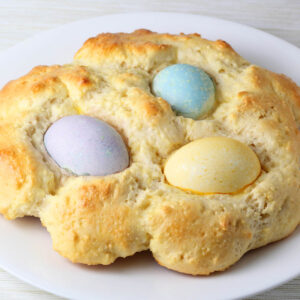 rounded loaf of protein bread with three colored easter eggs baked into it, the eggs are colored purple, blue, and yellow