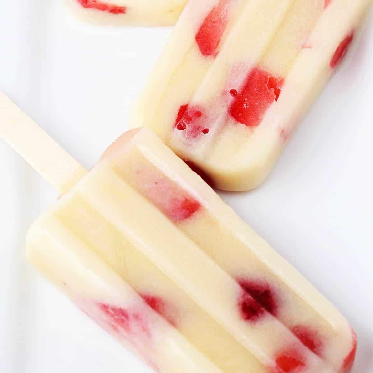 vanilla popsicles with strawberries on a white plate