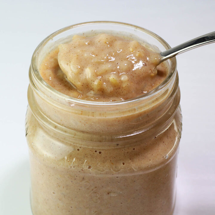 small mason jar full of rice pudding with a spoon pulling some out of the top with a light background