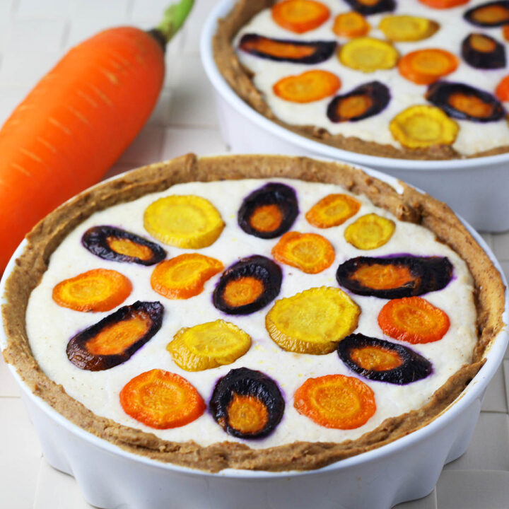 two mini ricotta tarts with sliced rainbow carrots in them and a large carrot on the side