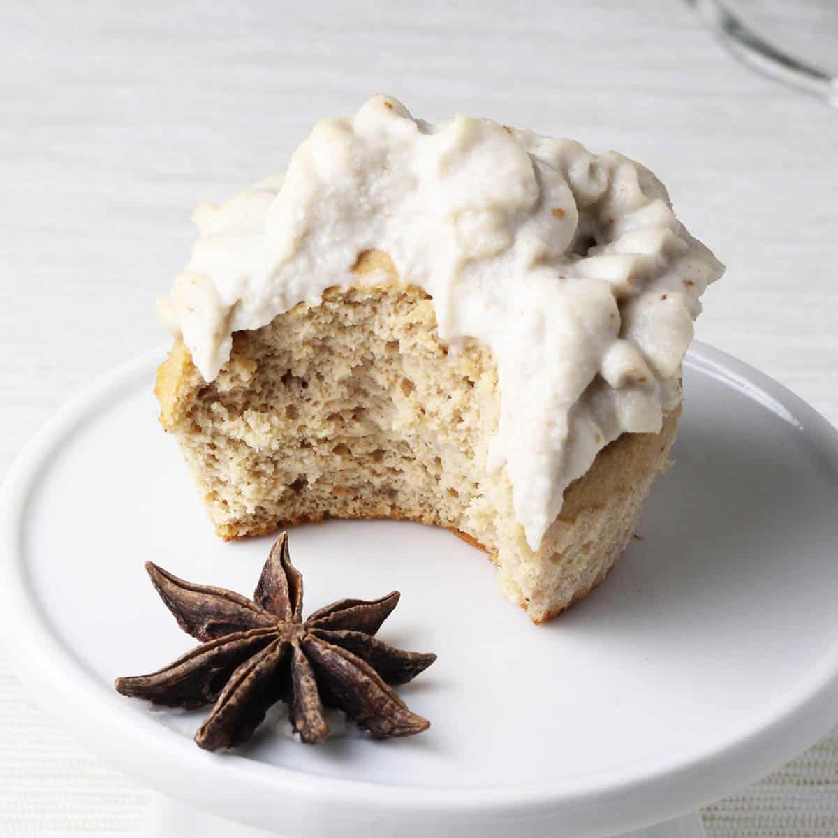 frosted bitten cupcake with a star anise in front on a white cupcake stand