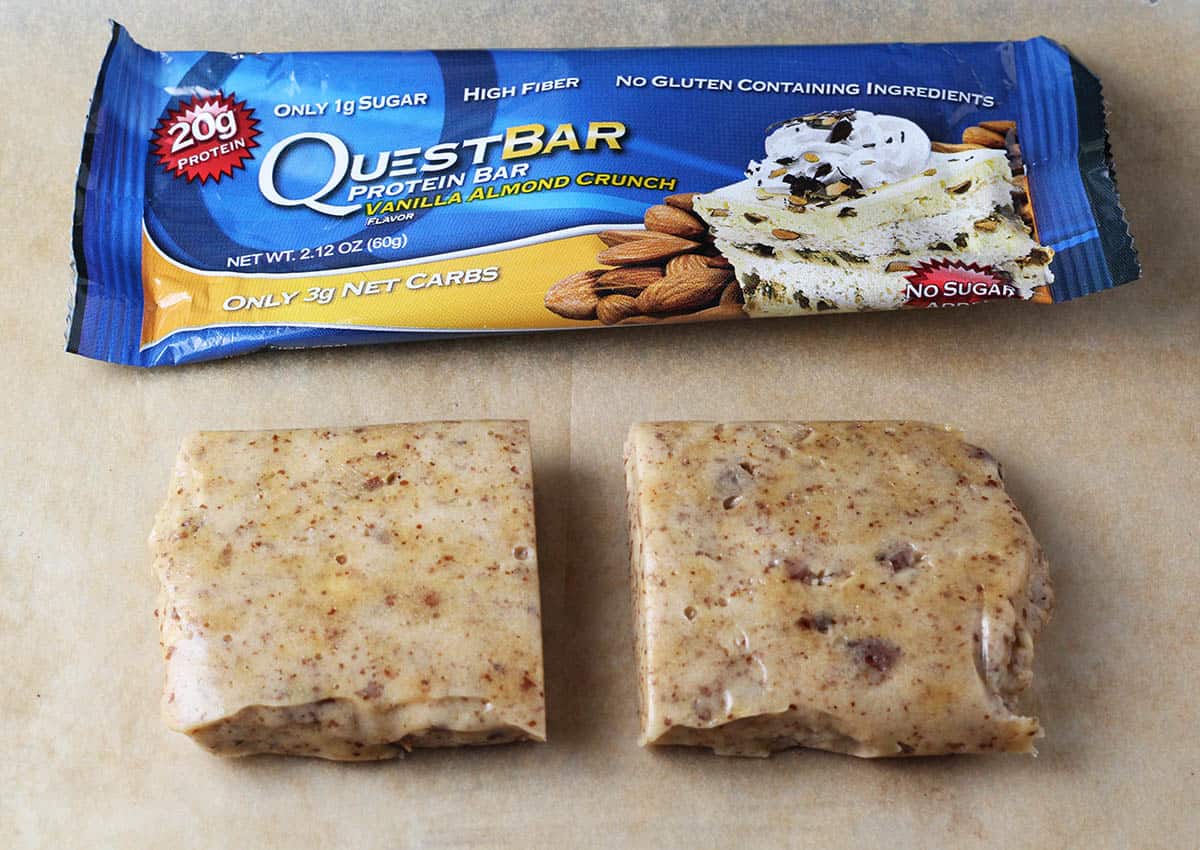vanilla almond quest bar cut into two pieces with the wrapper behind it