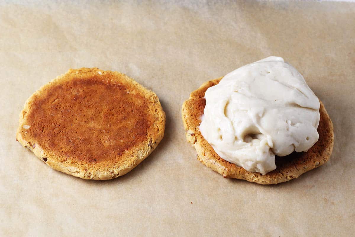 two large quest bar cookies, one with a scoop of protein ice cream on it