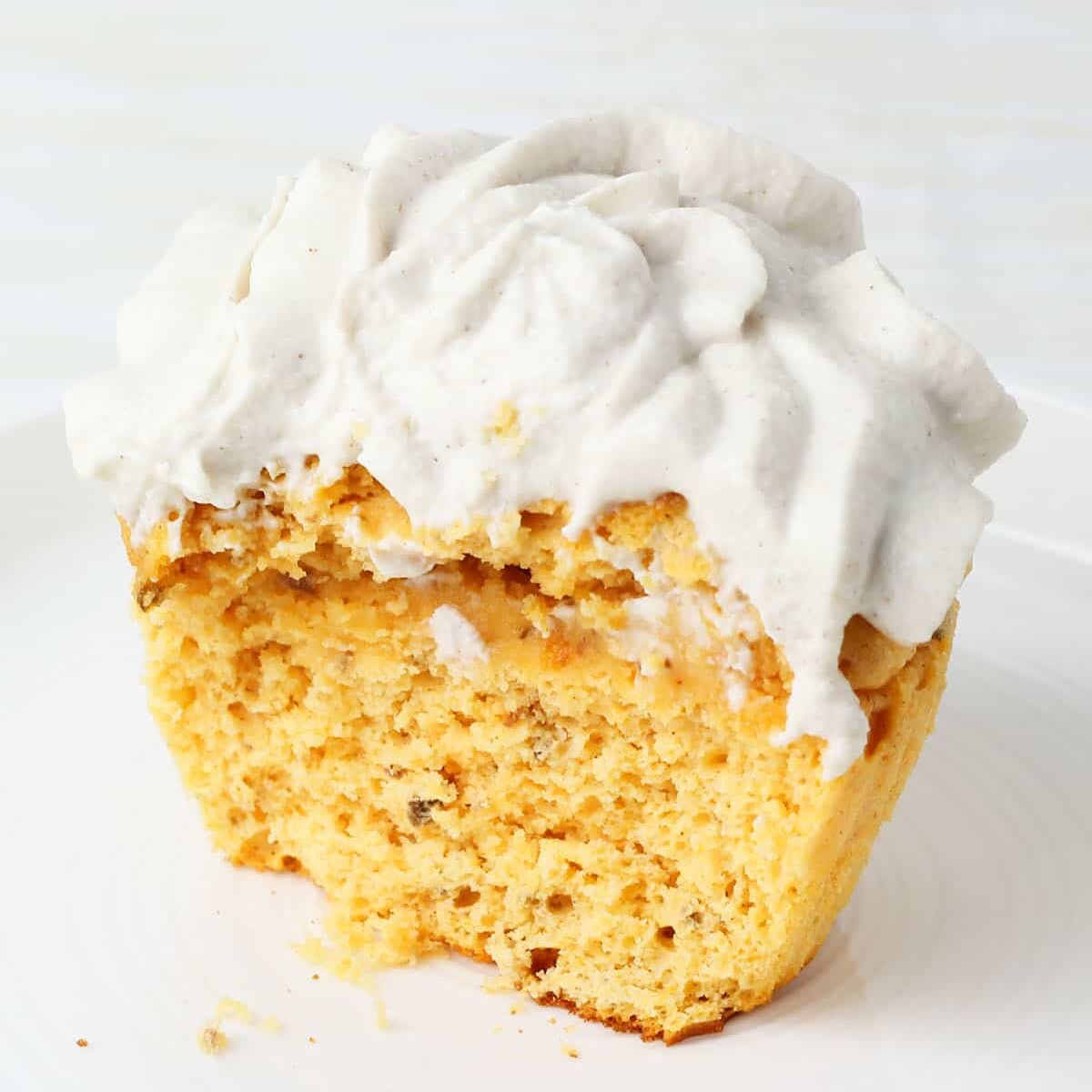 inside view of one frosted healthy sweet potato cupcake on a white plate