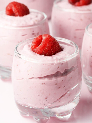 raspberry cheesecake mousse in shot glasses with a fresh raspberry on each