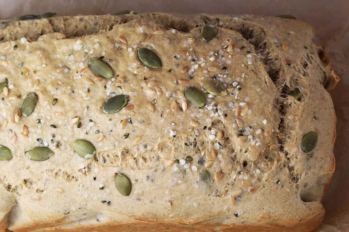 top view of a loaf of seeded bread, visible green pumpkin seeds