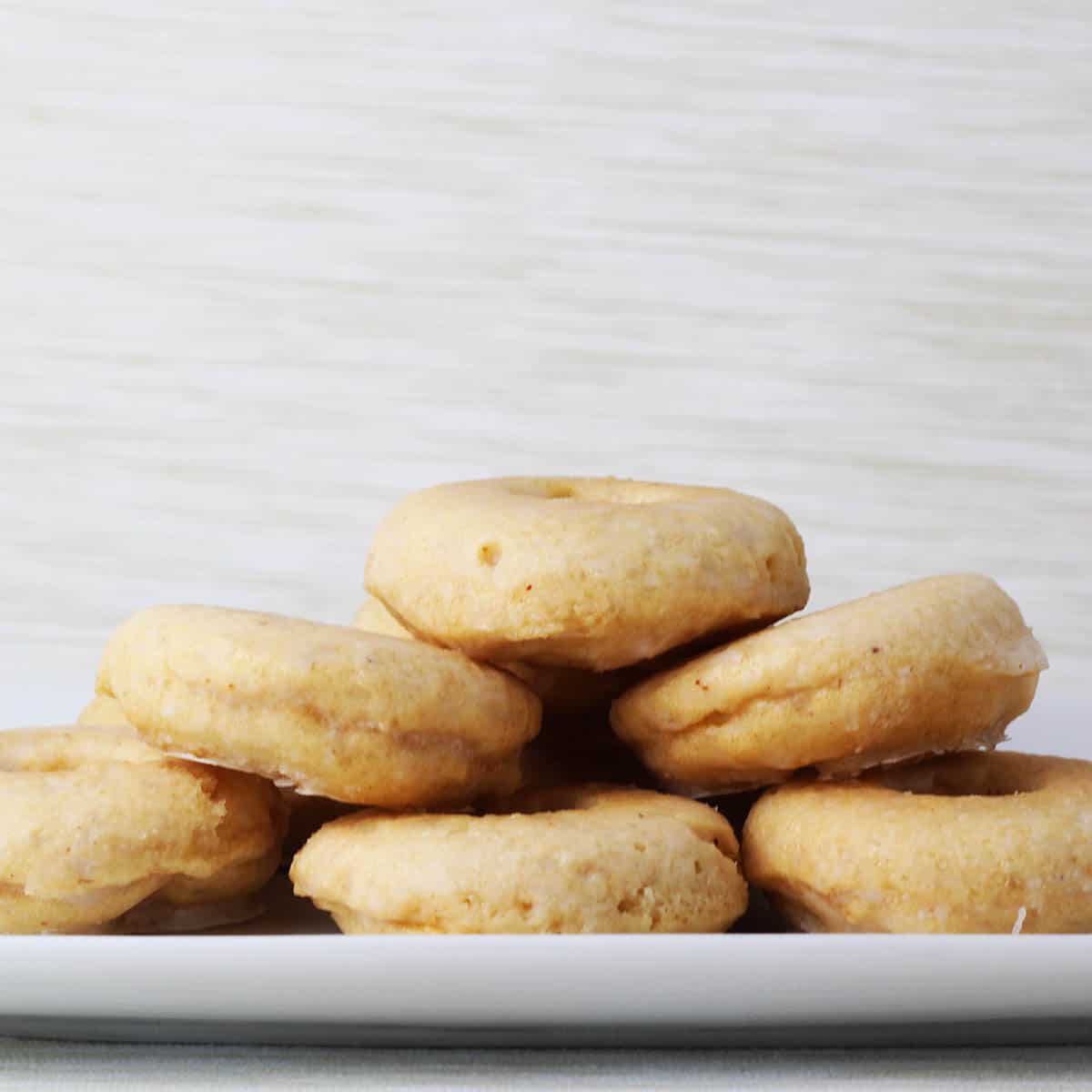 straight on view of a pile of mini donuts that are vanilla protein cake donuts with glaze