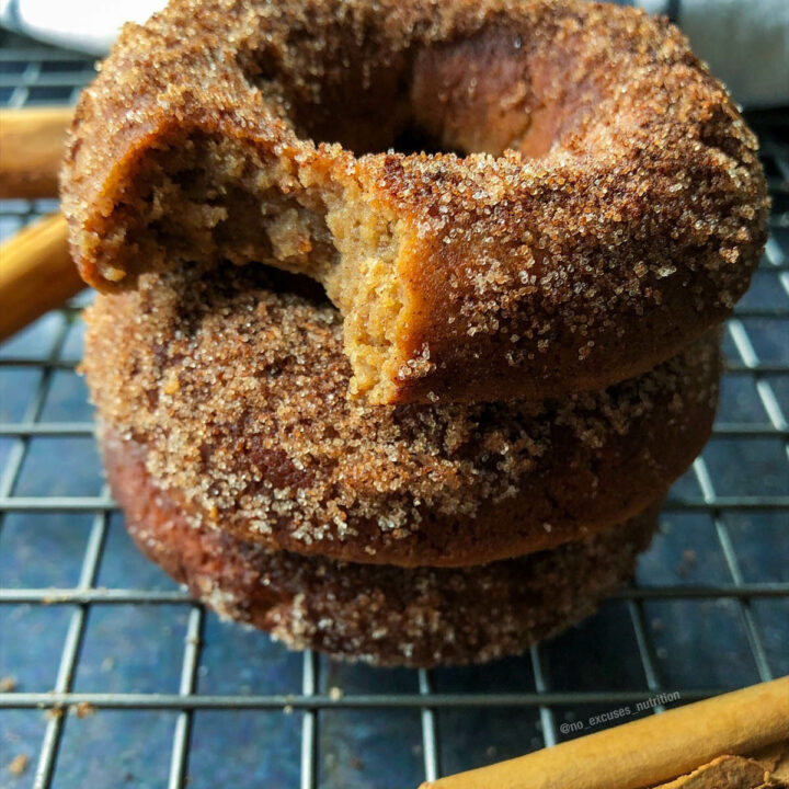 a stack of vegan apple cider donuts on a cooling rack with the top on bitten