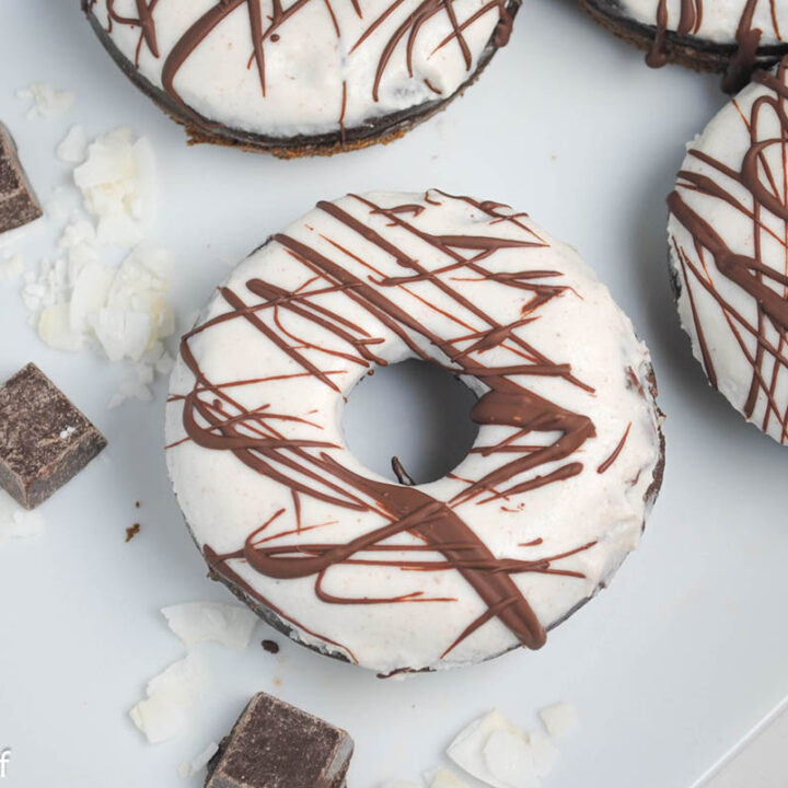 plate with chocolate donuts topped with white frosting and chocolate drizzle