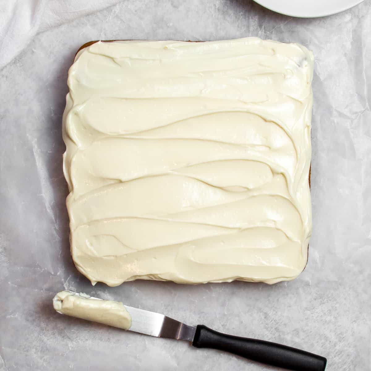 top view of a cake frosted with cream cheese protein frosting with frosting spatula below it