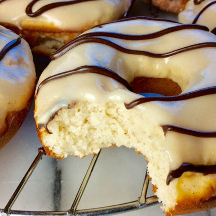 a bitten donut with white icing and chocolate drizzle