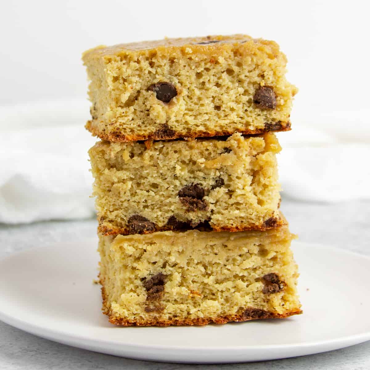 stack of three squares of vanilla chocolate chip protein snack cake on a white plate