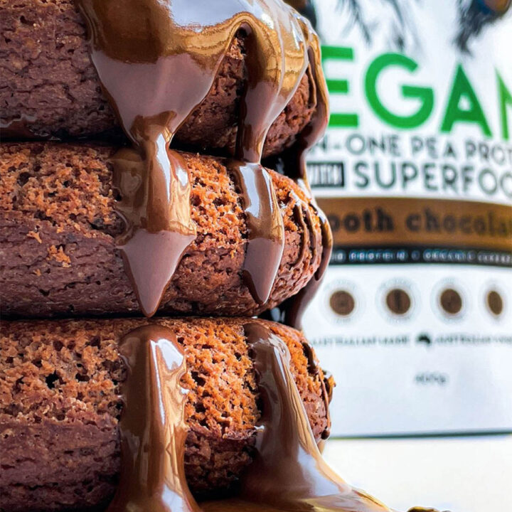 stack of chocolate protein donuts with a container of protein powder in the background