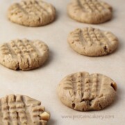 six peanut butter protein cookies on a parchment lined cookie sheet