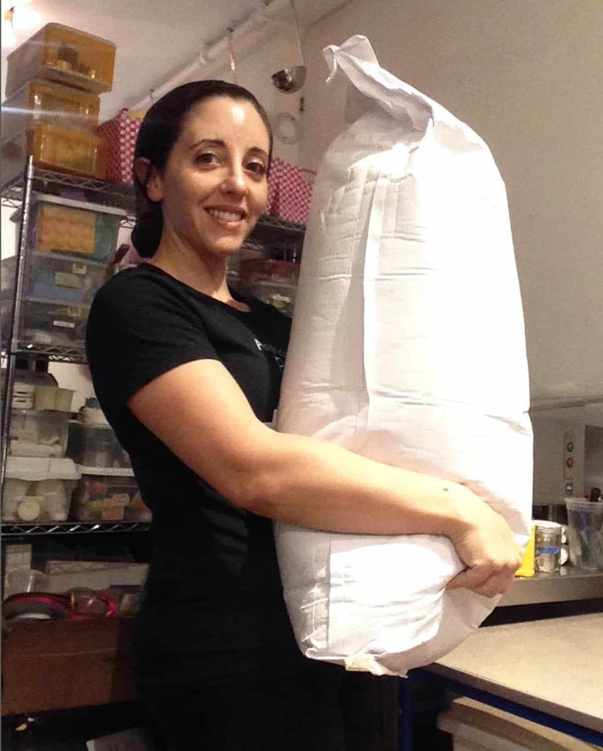 andrea in a bakery holding a giant bag of protein powder