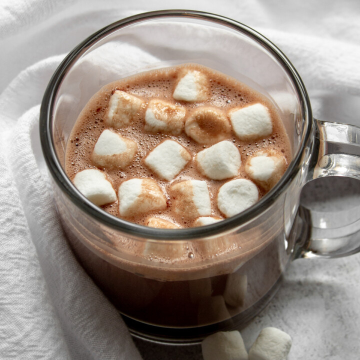 angled view of a glass mug with protein hot chocolate and mini marshmallows